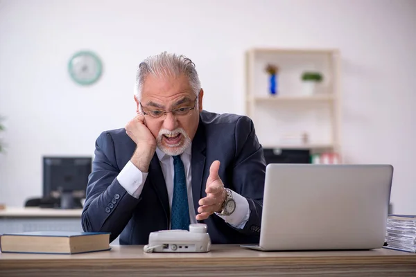 Velho funcionário masculino falando ao telefone no local de trabalho — Fotografia de Stock