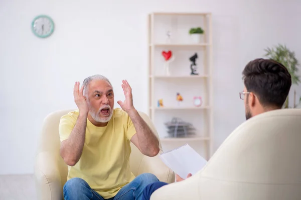 Viejo visitando joven psicoterapeuta masculino — Foto de Stock