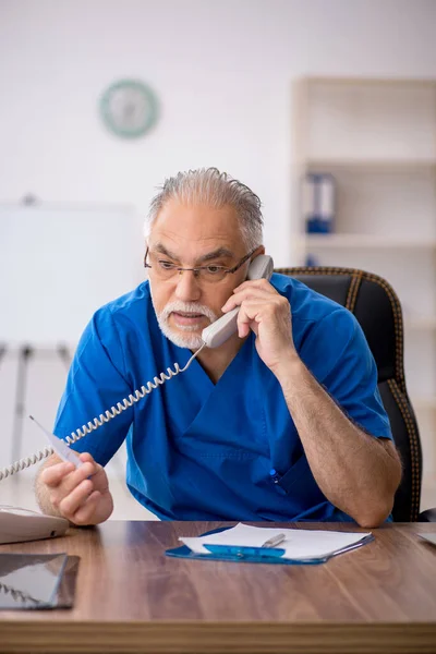 Starý lékař drží teploměr na klinice — Stock fotografie