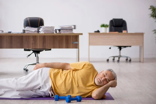 Старий працівник бізнесу робить спортивні вправи в офісі — стокове фото