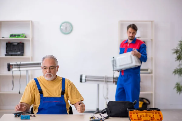Twee mannelijke monteurs aan het werk in de werkplaats — Stockfoto