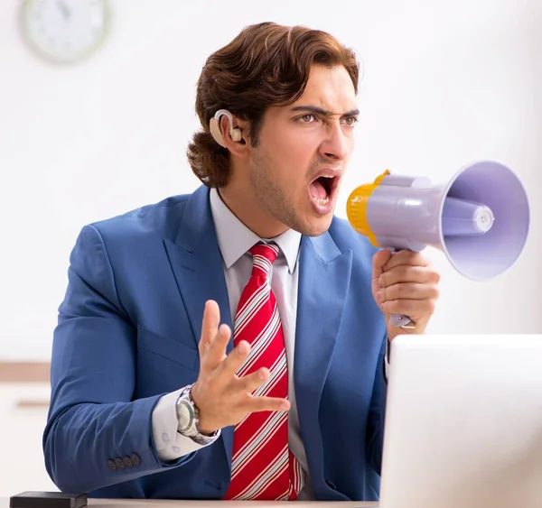 O empregado surdo usando aparelho auditivo no escritório — Fotografia de Stock