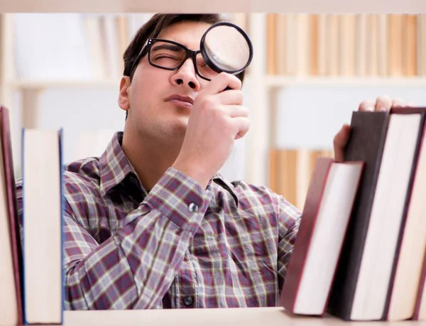 Joven estudiante en busca de libros en la biblioteca universitaria — Foto de Stock