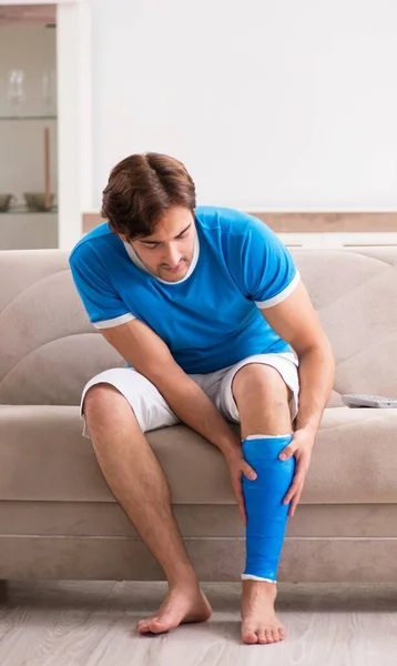 Junger Mann auf dem Sofa am Bein verletzt — Stockfoto