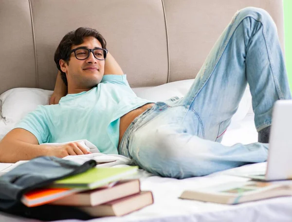 Φοιτητής που προετοιμάζεται για τις εξετάσεις στο σπίτι στο υπνοδωμάτιο ξαπλωμένος στο κρεβάτι — Φωτογραφία Αρχείου