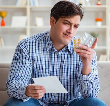 Kanepede ilaç ve reçeteyle oturan genç adam.