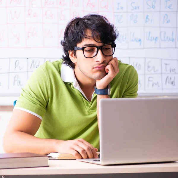 Молодий студент-хімік перед періодичною таблицею — стокове фото