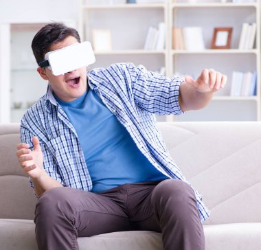 Evde sanal gerçeklik gözlüklü bir adam oynuyor.
