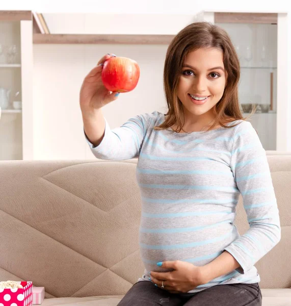 La giovane donna incinta seduta sul divano di casa — Foto Stock