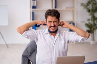 Genç erkek çalışan ofiste oturuyor.