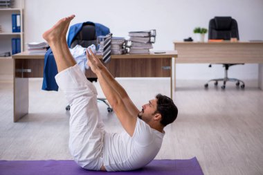 Genç erkek çalışan ofiste spor egzersizleri yapıyor.