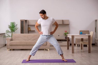 Genç adam evde spor yapıyor.