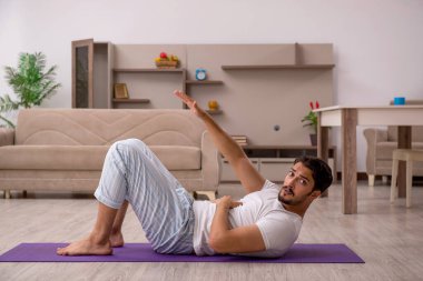 Genç adam evde spor yapıyor.