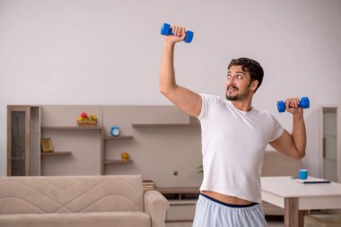 Genç adam evde spor yapıyor.