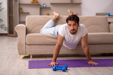 Genç adam evde spor yapıyor.