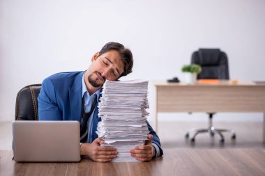 Ofisteki aşırı işten memnun olmayan genç bir erkek işçi.