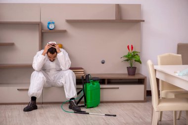 Genç erkek müteahhit evde haşere kontrolü yapıyor.