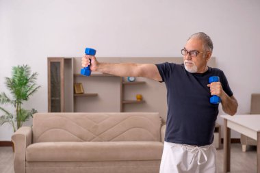 Yaşlı adam evde spor yapıyor.