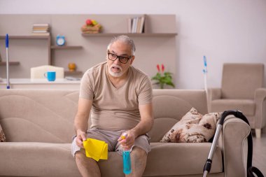 Yaşlı adam evde ev işi yapıyor.