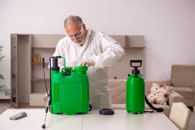 Yaşlı erkek müteahhit evde haşere kontrolü yapıyor.