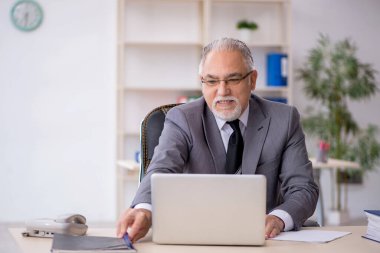 Ofiste çalışan yaşlı bir erkek.