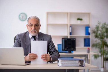 Ofiste çalışan yaşlı bir erkek.