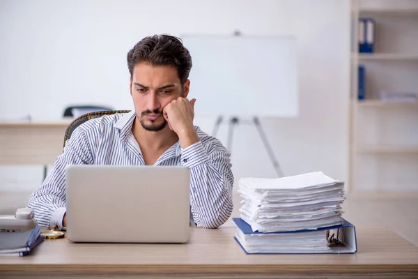 Joven empleado masculino y demasiado trabajo en la oficina — Foto de Stock