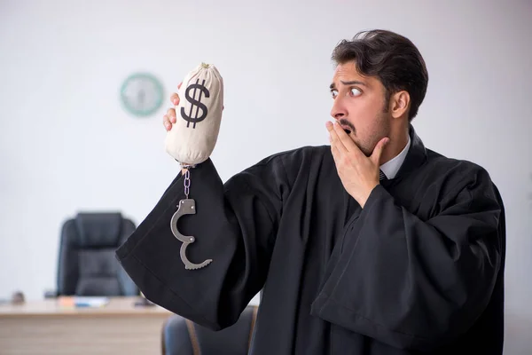 Jeune juge homme tenant sac d'argent dans le concept de corruption — Photo