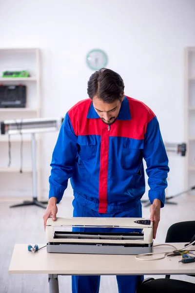 Jonge mannelijke reparateur repareert airconditioner — Stockfoto