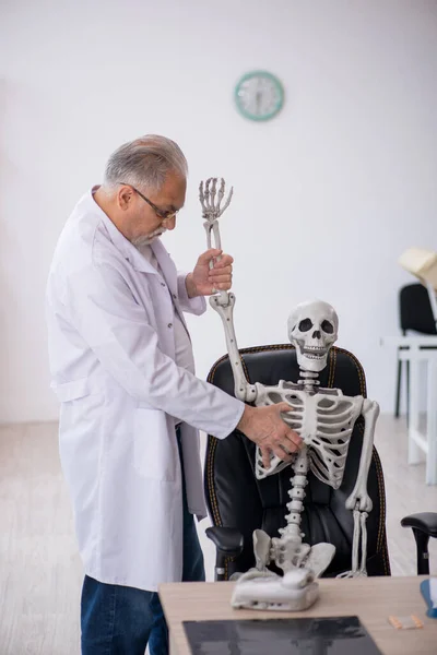 Viejo doctor con esqueleto en la clínica — Foto de Stock