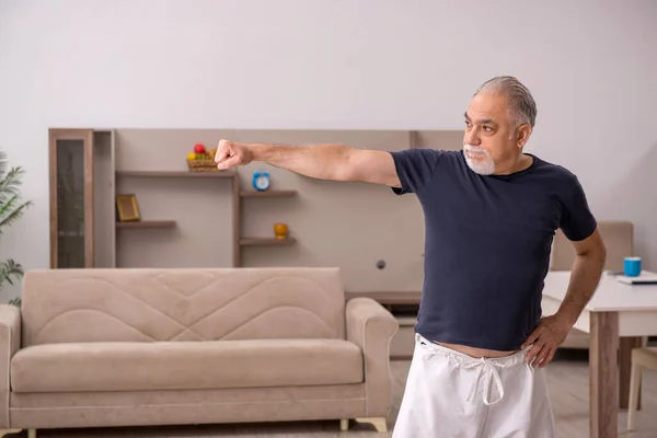 Öreg ember sporttevékenységeket végez otthon — Stock Fotó