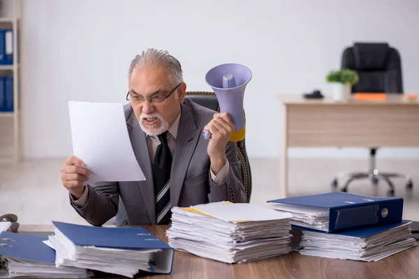 Starý muž zaměstnanec držící megafon v kanceláři — Stock fotografie