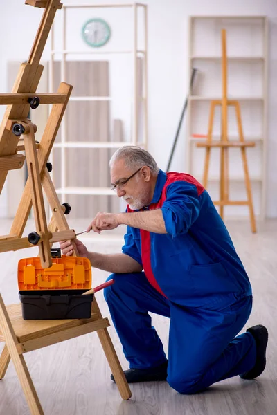 Oude mannelijke timmerman repareert schildersezel — Stockfoto