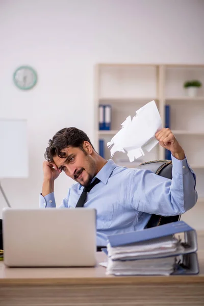 Joven empleado masculino descontento con el trabajo excesivo en la oficina Imagen De Stock