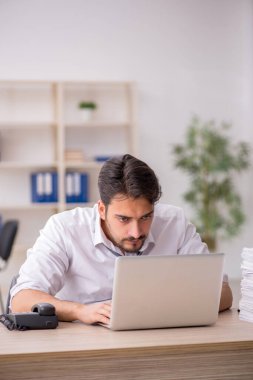 Genç bir erkek çalışan ve ofiste çok fazla iş var.