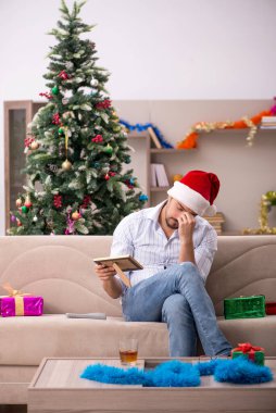 Genç adam Noel 'i evde yalnız kutluyor.