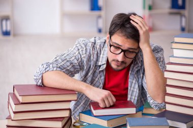 Genç bir erkek öğrenci ve sınıfta çok fazla kitap var.