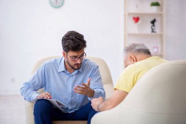 Yaşlı adam genç erkek psikoterapisti ziyaret ediyor.
