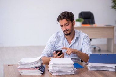 Genç bir erkek çalışan ve ofiste çok fazla iş var.