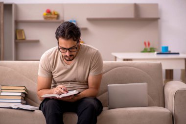 Genç erkek öğrenci salgın sırasında evde çalışıyor.