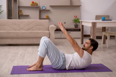 Genç adam evde spor yapıyor.