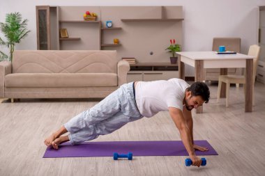 Genç adam evde spor yapıyor.