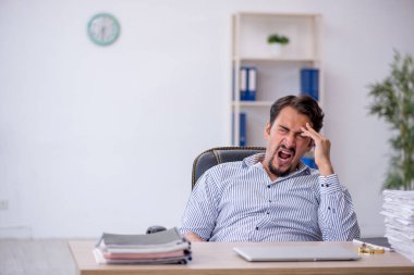 Ofisteki aşırı işten memnun olmayan genç bir erkek işçi.