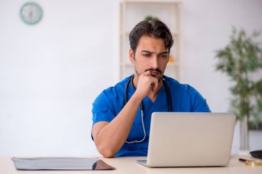 Klinikte çalışan genç erkek doktor.