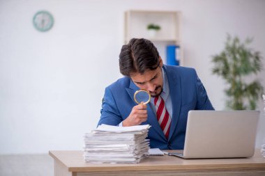 Genç bir erkek çalışan ve ofiste çok fazla iş var.