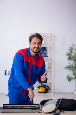 Klimayı tamir eden genç bir erkek tamirci