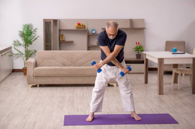 Yaşlı adam evde spor yapıyor.