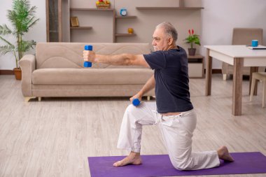 Yaşlı adam evde spor yapıyor.