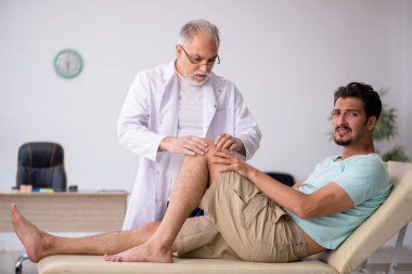 Genç erkek hasta yaşlı erkek doktoru ziyaret ediyor.