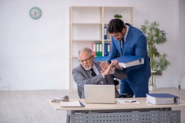 Yaşlı erkek patron ve ofiste çalışan genç erkek çalışan.